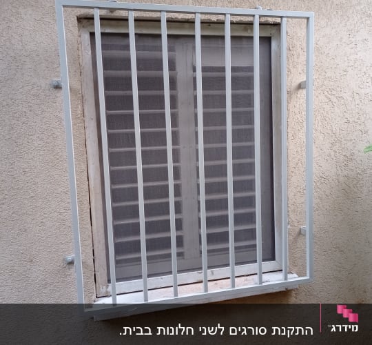 סורגי מתכת לבנים על חלון עם תריסים